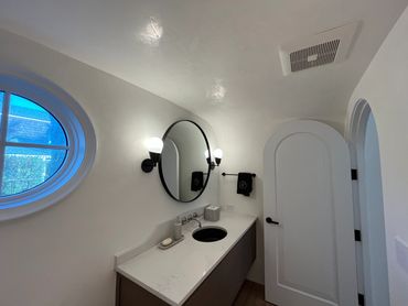 Minimalist bathroom with round mirror and oval window.