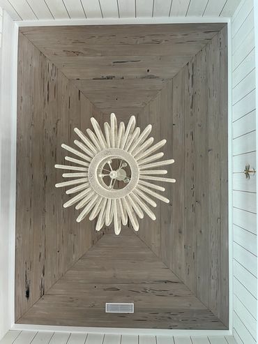 Decorative ceiling with wooden panels and a sun-shaped light fixture.