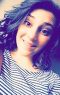 A young woman smiling with wavy hair and striped shirt.