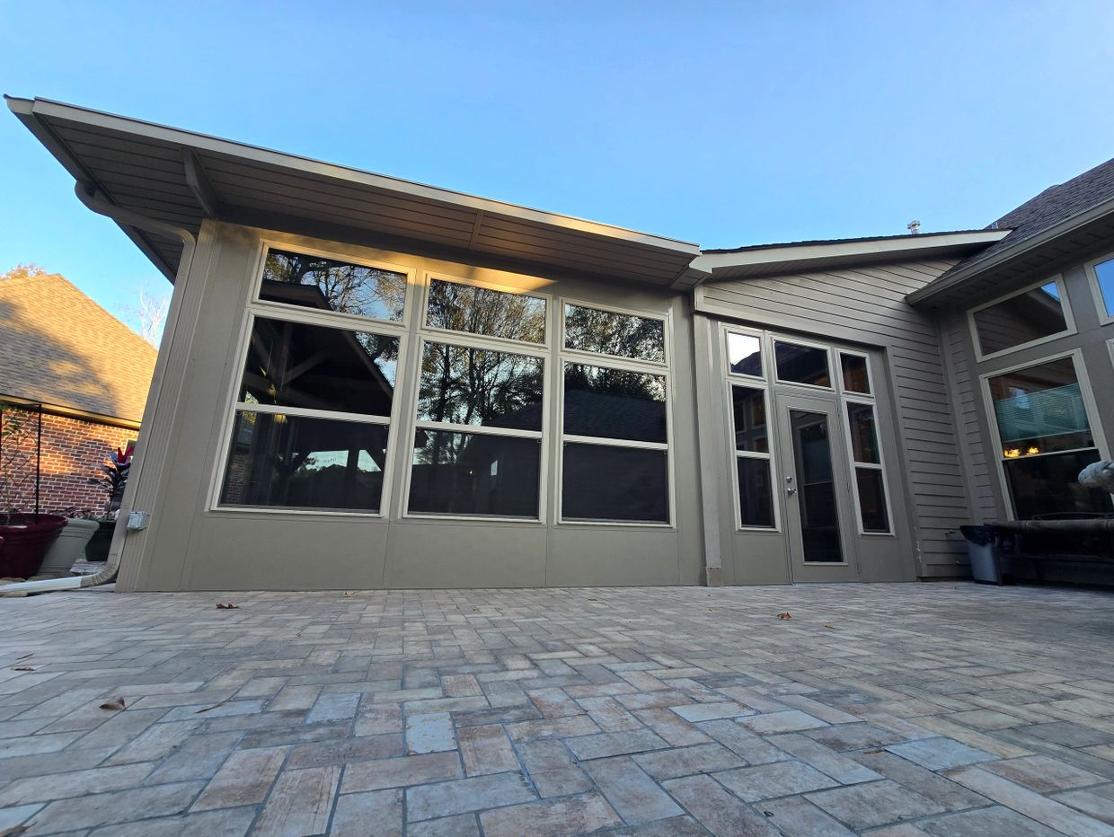 Spacious patio with large windows and stone tile flooring on a clear day.