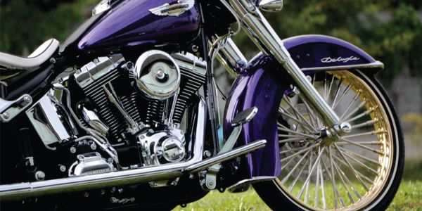 Close-up of purple and gold motorcycle engine and front wheel.