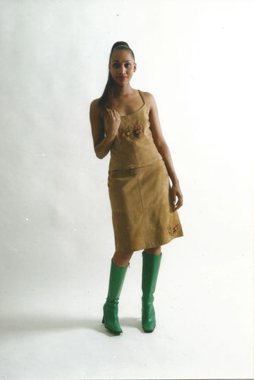 Woman in a brown dress with floral details and green boots.
