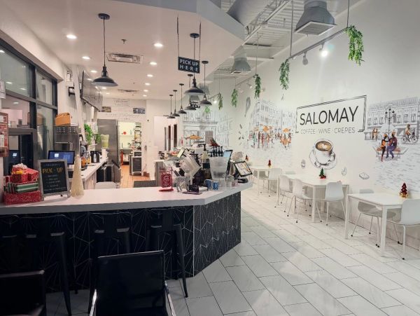 Modern cafe interior with white walls and black counter seating.