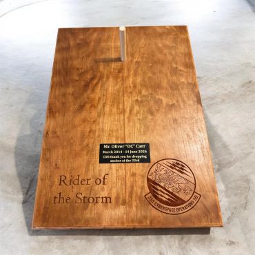 Wooden memorial plaque honoring Mr. Oliver "OC" Carr with engraved text and logo.