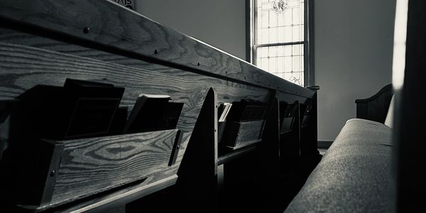 Interior of a church with wooden pews and a stained glass window.