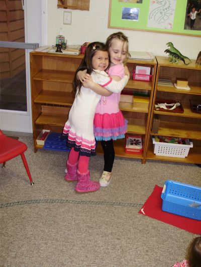 Two young girls happily hugging each other indoors.