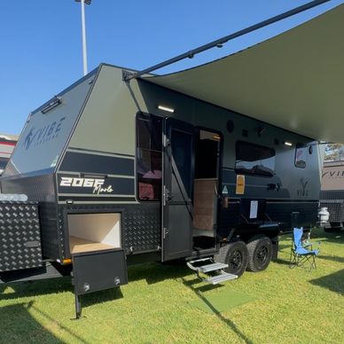 Black and gray Vibe 206F bunk caravan with an extended awning on grass.