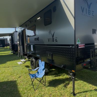 Modern Vibe caravan parked on grass with a blue folding chair outside.