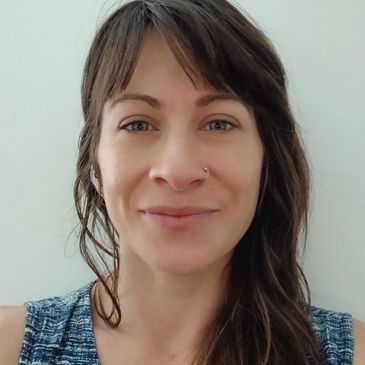 Smiling woman with long brown hair and nose ring.