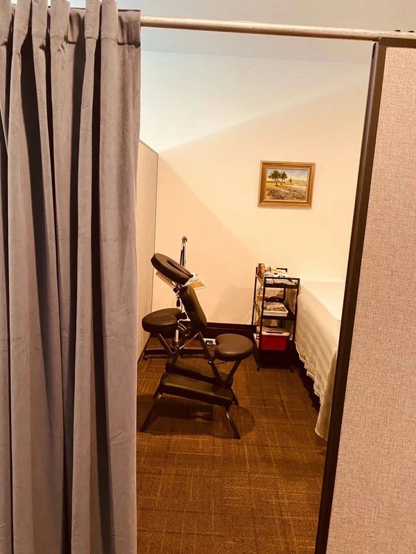 A massage chair in a cozy treatment room with a curtained entrance.