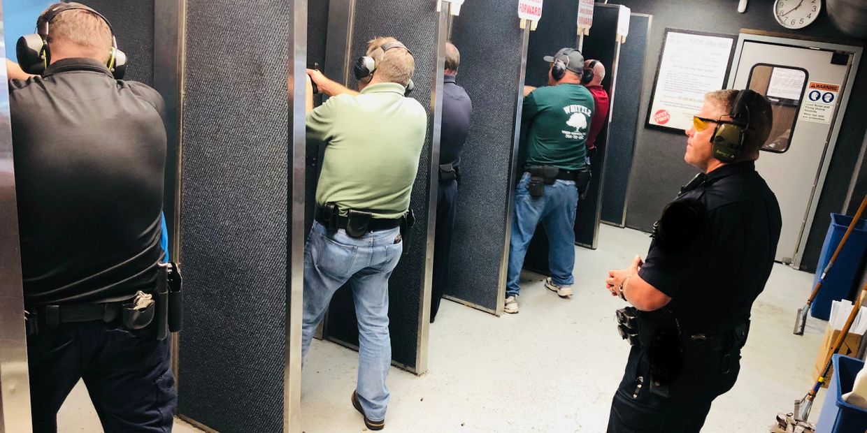 People at a shooting range practicing with firearms under supervision.