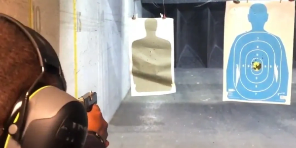 Person wearing ear protection shooting at a target range.