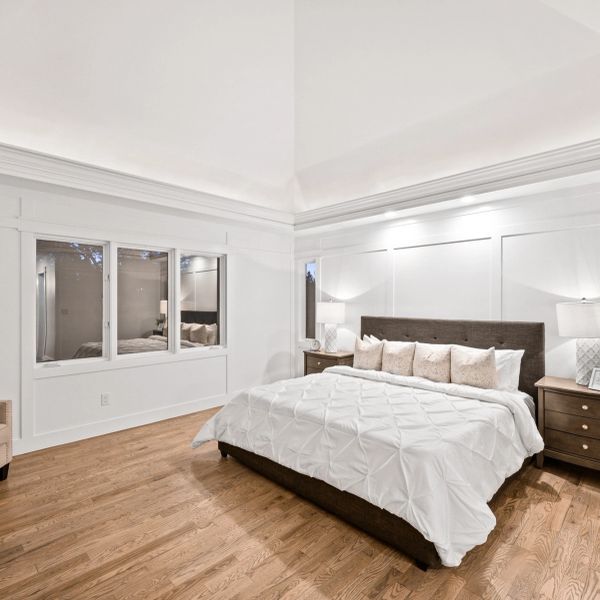 Minimalist bedroom with white walls and wooden floor.