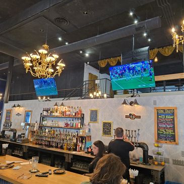 Back bar in Jamestown TV's, Liquor, taps, and seltzer flavors. The main Chandelier shines brightly.