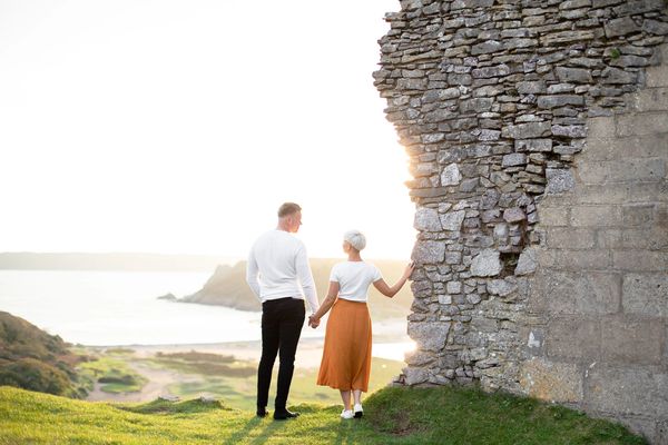 Couple overlooks the ocean and a valley from castle ruins