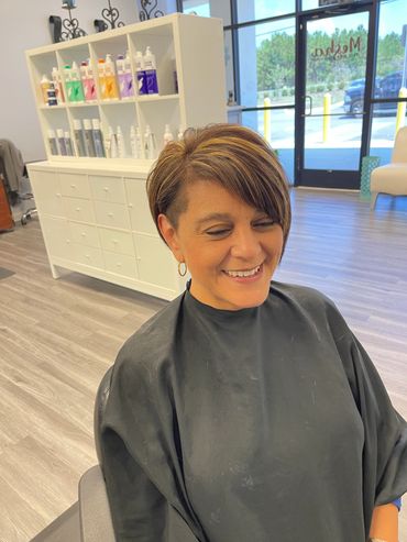 Woman with a short hairstyle smiling in a salon.