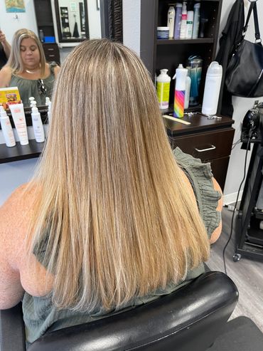 Woman with long, straight blonde hair at hair salon.