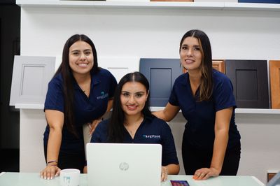 Three Keystone Kitchen & Bath employees smile at the camera.  One sits at a laptop.