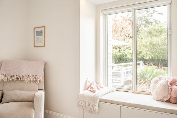 Cozy beige armchair and window seat with soft cushions and throw blanket.