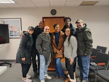 Group of seven people posing indoors, smiling.
