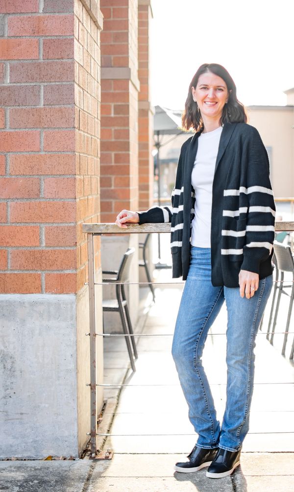 Founder Erin, standing next to a brick wall with a big smile.