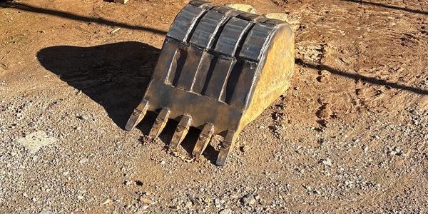 Close-up of an excavator bucket on dry soil.