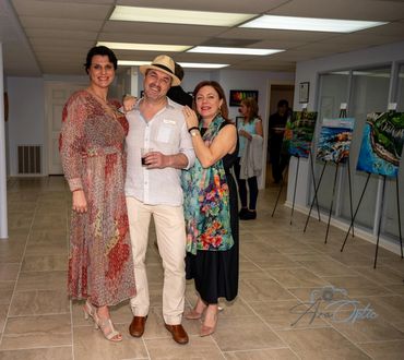 Three people smiling at an art gallery.