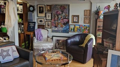 View of gallery art wall with chairs, tables and games