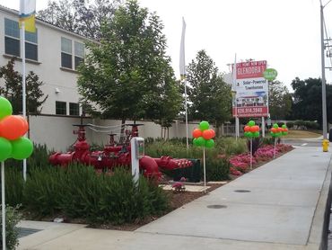Sidewalk with colorful balloons and large red valves near residential buildings.