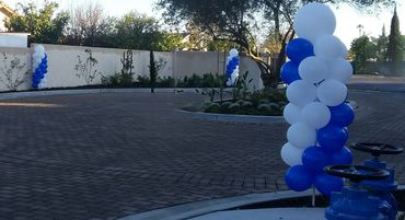 Blue and white balloon columns decorate an outdoor paved area.