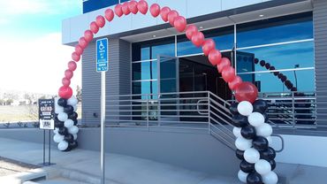 Red, black, and white balloon arch outside a building.