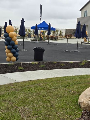 Outdoor event setup with balloons, umbrellas, and a blue canopy tent.