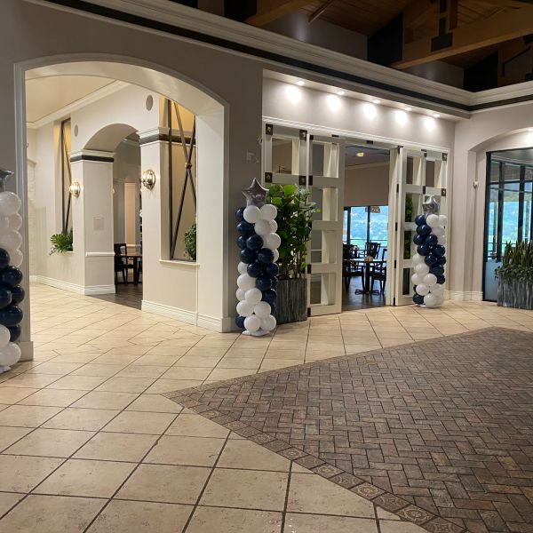 Elegant entrance decorated with balloon columns in white and navy.