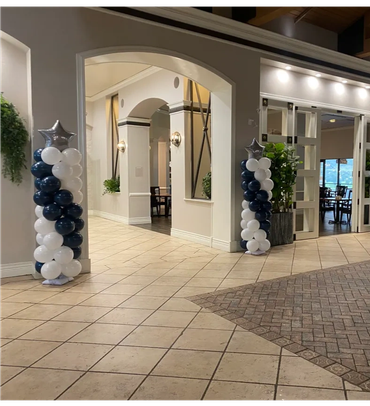 Balloon columns with star toppers flank an elegant archway in a spacious venue.