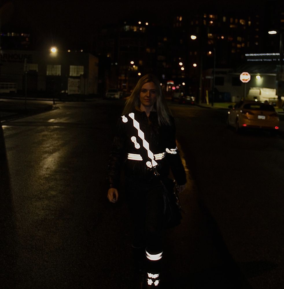 person walking down a dark street with light reflective accessories illuminating them.