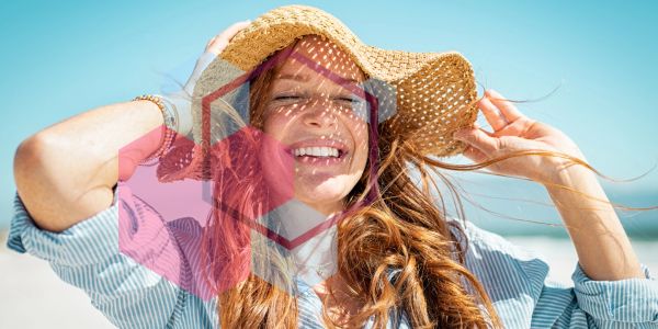 Smiling woman enjoying sunny day at the beach with a straw hat.