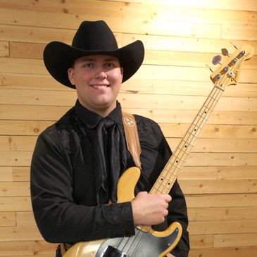 Man in cowboy hat holding an electric bass guitar.