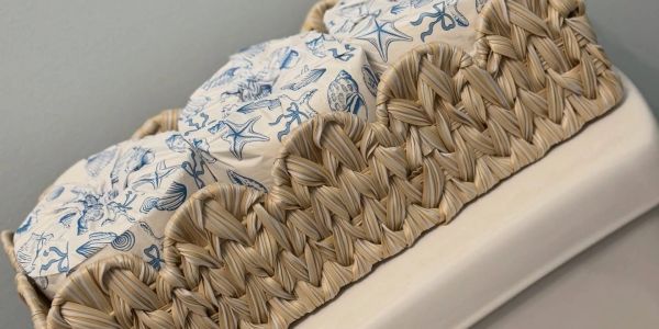 Woven basket holding patterned cushions with sea-themed designs.