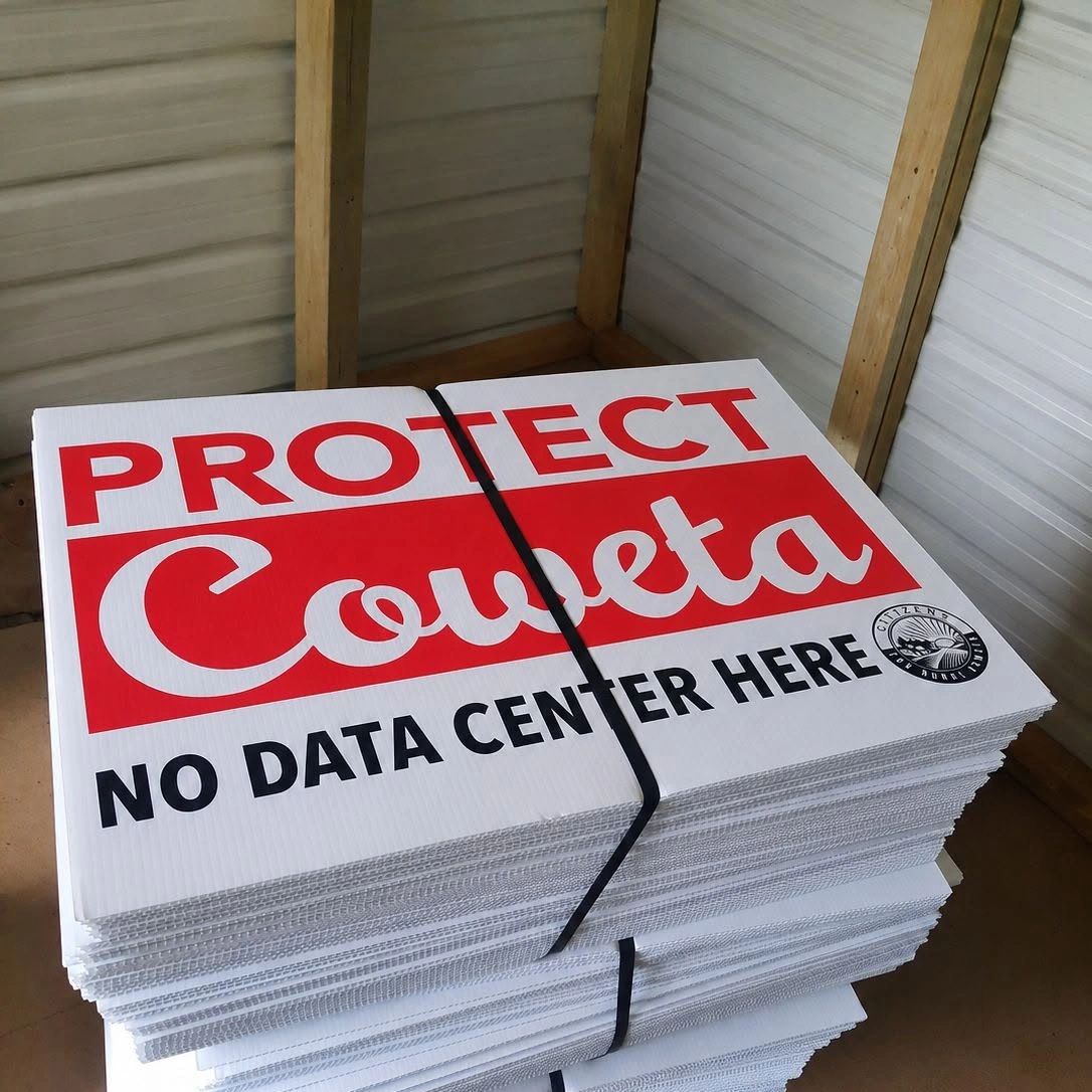 Stacked protest signs saying "Protect Coueta, No Data Center Here."