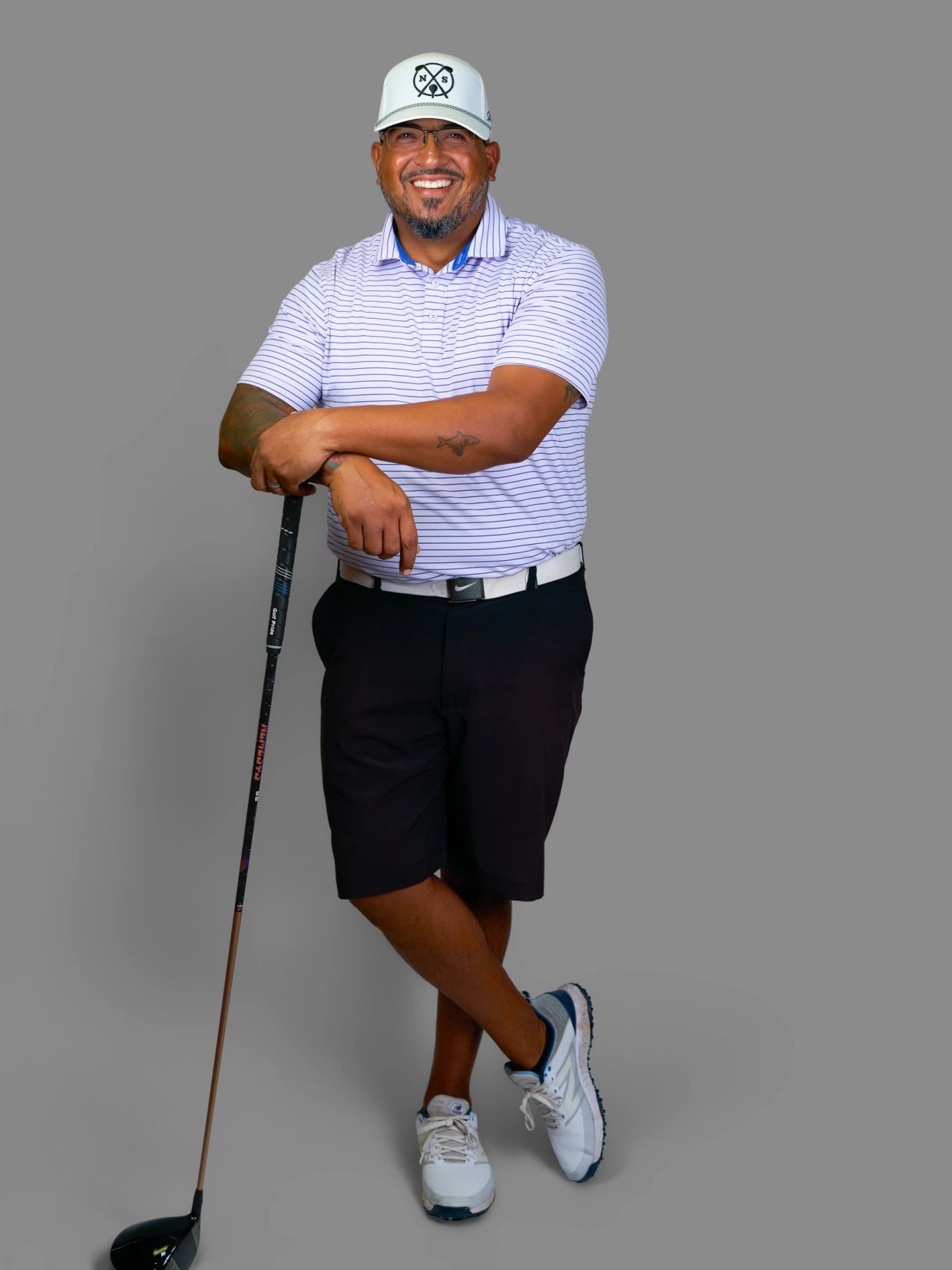 Smiling man in golf attire holding a golf club.