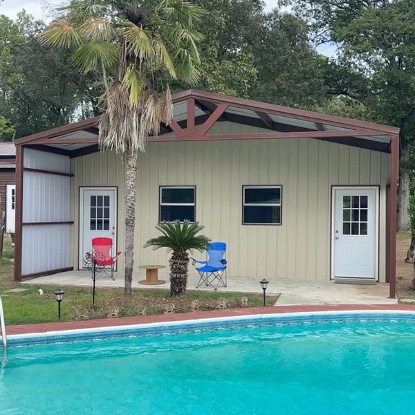 Backyard pool with a small covered patio and two chairs.