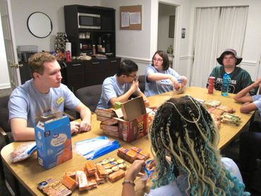 Group of people sitting around a table with snacks and drinks, engaged in conversation.