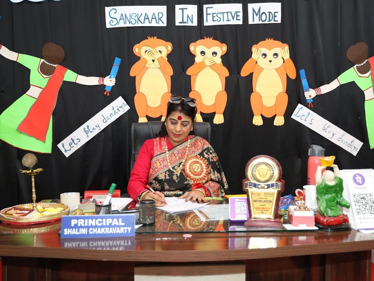 Principal Shalini Chakravarty at her desk with festive decorations.