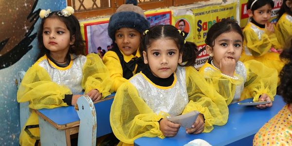 Children in yellow costumes sitting at desks.