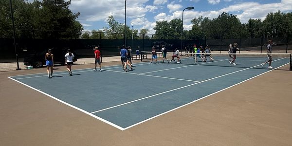 Group of people walking on a tennis court on a sunny day.