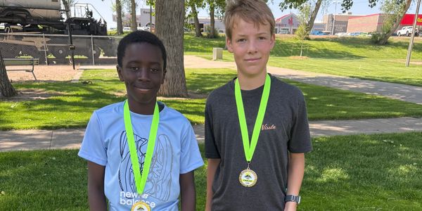Two boys outdoors wearing medals around their necks.