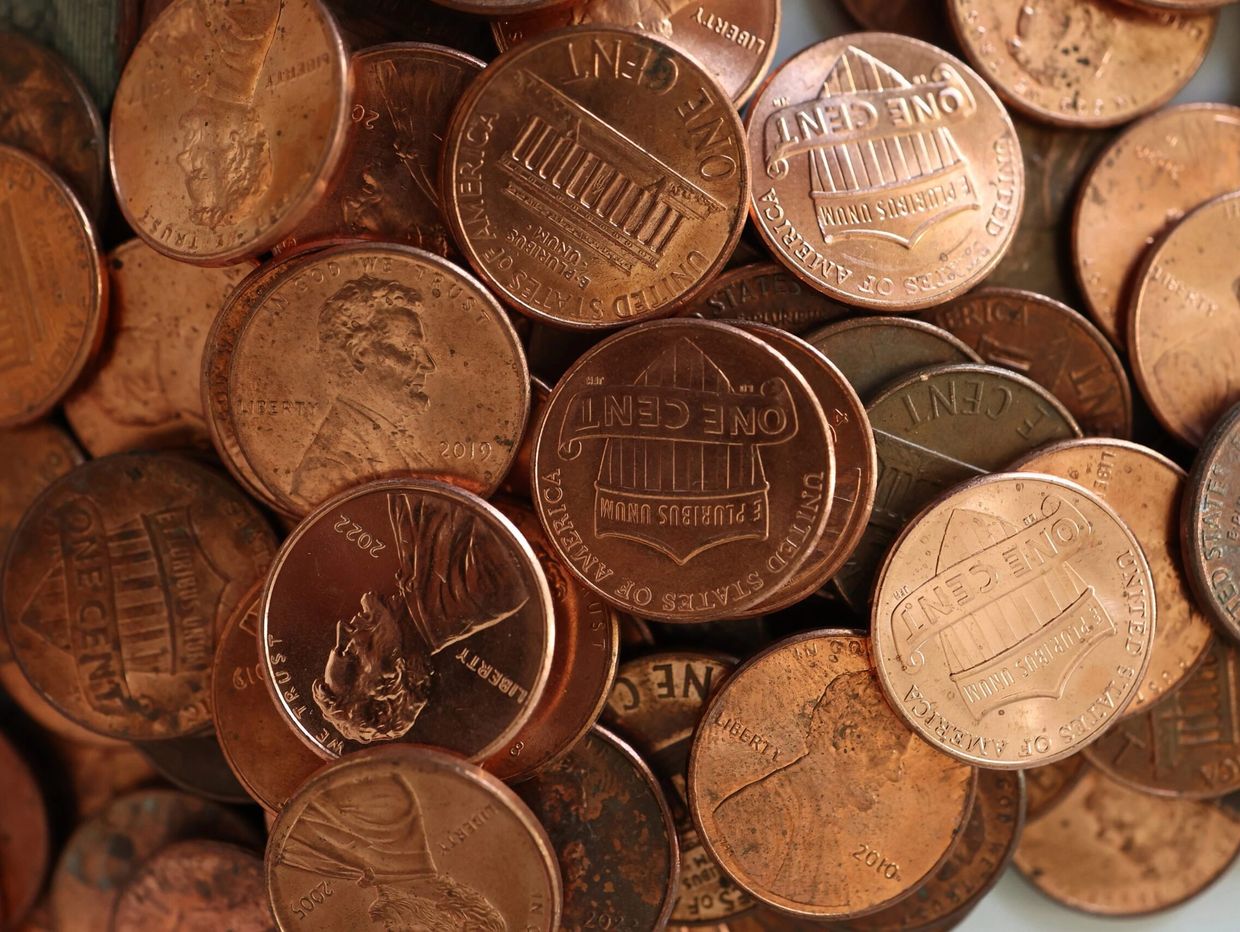 A close-up of scattered US pennies showing heads and tails.
