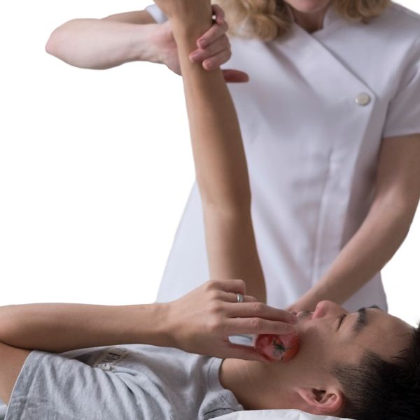 A therapist stretches a patient's arm while he holds a tomato to his face.