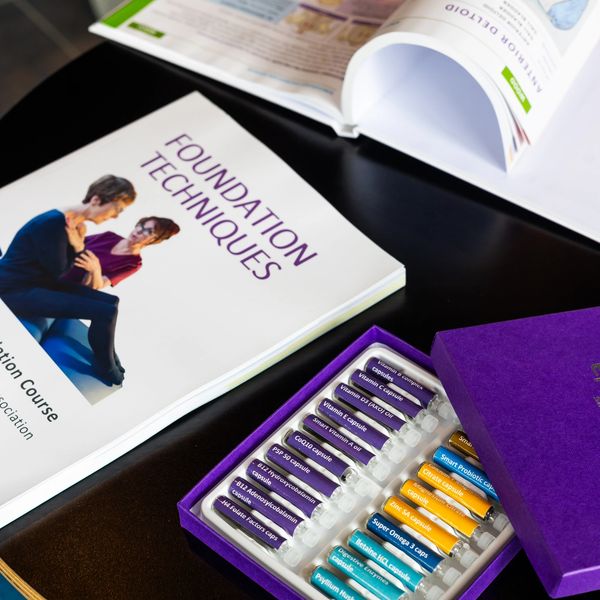 A foundation techniques book beside a colorful vitamin capsule set in a purple box.