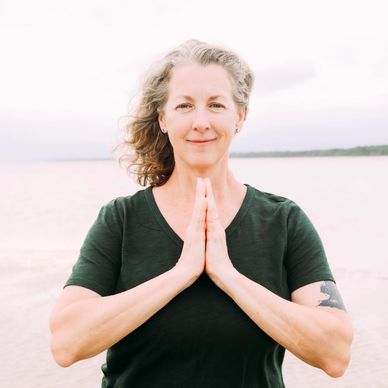 Woman practicing meditation outdoors by the water.